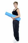 Smiling Female Instructor Carrying A Blue Yoga Mat Stock Photo