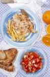 Turkey Steak With French Fries And Tomato Salad Stock Photo