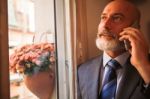 Middle-aged Businessman Listening On Smartphone At Home Stock Photo