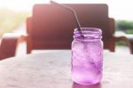 Iced Drink In Violet Glass In Coffee Shop Stock Photo