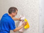 Man Smoothing The Wallpaper With A Spatula Stock Photo