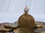 Miniature Businessman Sit On Euro Coins And Book Bank. Business Stock Photo