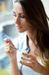 Young Woman At Home Eating Yogurt Stock Photo