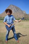 Man Standing And Playing Folk Guitar With Mountain Behind Stock Photo