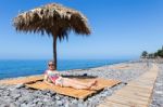 Woman Sunbathing As Tourist On Stony Portuguese Beach Stock Photo