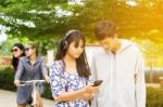 Group Of Asian Teenager Walking In The Park And Enjoyed Watching Video From Smartphone  Stock Photo