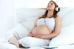 Pregnant Woman Sitting On Sofa At Home And Listening Music In He Stock Photo