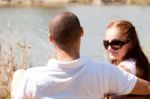 Couple Sitting At Lake Side Stock Photo