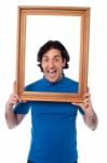 Excited Young Male Holding Wooden Frame Stock Photo