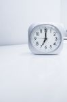 White Square Clock On White Bed Stand With White Wallpaper Background, Morning Time In Minimal Style Decoration Stock Photo