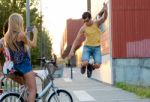 Young Man With Roller Skates Jumping And Girls Taking A Photo Stock Photo