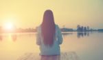 Silhouette Of Relaxing Young Woman On Wooden Pier At The Lake In Sunset Stock Photo