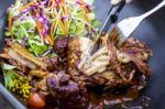 Steak Knife And Fork Slicing Grilled Rib Eye Beef Steak With Vegetable Salad In Black Bowl Stock Photo