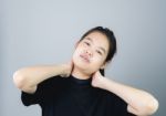 Asian Girl In Black Casual Dress Catch That Shoulder, Because Of The Pain Of Hard Work. Or Something Hit The Shoulder. On A Gray Background Gives A Soft Light Stock Photo