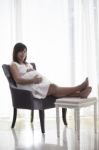 Young Woman Pregnant Sitting On Arm Chairs In Home Living Room W Stock Photo