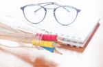 Pencils In Bottle With Eyeglasses On Notebook Stock Photo