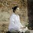 Asian Woman Meditating In Ancient Buddhist Temple