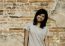 Girl Posing And Smiling While Standing Near Brick Wall