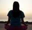 Young Woman Meditating On Beach