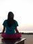 Woman Meditating On The Beach At Sunset