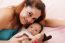 Happy Mum And Baby Boy Smiling In The Bed Holding Teddy Bear