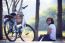 Asian Woman Sitting In The Park With Bicycle In Morning