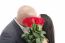 Two Young Dates Kissing Behind A Bouquet Of Red Roses