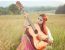 Hippie Girl Playing Guitar On Grass