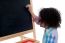 Young School Child Writing On Blackboard