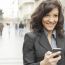 Young Woman With Smile And Smartphone Walking On Street