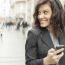 Young Woman With Smartphone Walking On Street