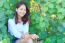 Portrait Of Pretty Woman Sitting In Green Leaves Bush And Smilin