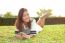 Portrait Of Beautiful Young Woman Lying On Green Grass Field And