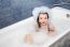 Surprised Little Girl Sitting In A Bath With Soap Suds