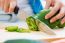 Woman Hand Cutting A Green Pepper In Kitchen