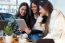 Three Young Woman Using Digital Tablet At Cafe Shop