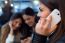 Three Young Woman Using Mobile Phone At Cafe Shop