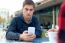 Young Entrepreneur Using His Mobile Phone At Coffee Shop