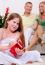 Cute Girl Opening Christmas Gift With Parents In The Background