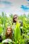 Two Young Girls Hiding In A Green Cornfield