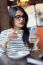 Young Beautiful Woman Using Her Mobile Phone In Coffee