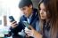 Young Couple Using Mobile Phone In Cafe