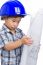 Adorable Future Engineer Wearing Blue Helmet On White Background. Boy Holding A Blueprint