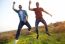 Portrait Of Two Friends Jumping In Field