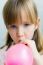 Cute Little  Girl Inflating A Pink Balloon In The Kitchen