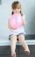 Cute Little  Girl Inflating A Pink Balloon In The Kitchen