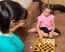 Little Girl Playing Draughts With Her Mother