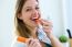 Pretty Young Woman Eating Carrot In The Kitchen