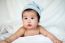 Sweet Newborn Baby In White Hat Lies On Bed