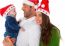 Happy Parents With Baby Boy Wearing Santa Hats